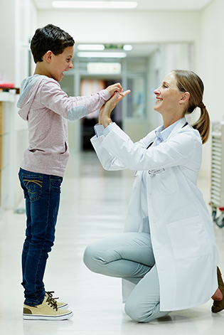Doctor giving high-five to boy in corridor