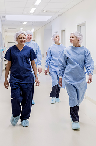Surgical team walking down hospital corridor, front view