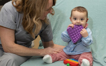 A baby and nurse playing with a sensory toy in a hospital bed