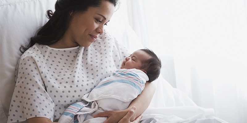 Mother in hospital bed holding newborn baby girl