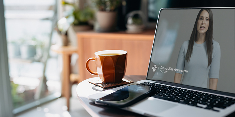 Cropped shot of laptop, smartphone and a cup of tea in the living room at home, HCA's Postpartum Health video appears on the screen of the laptop